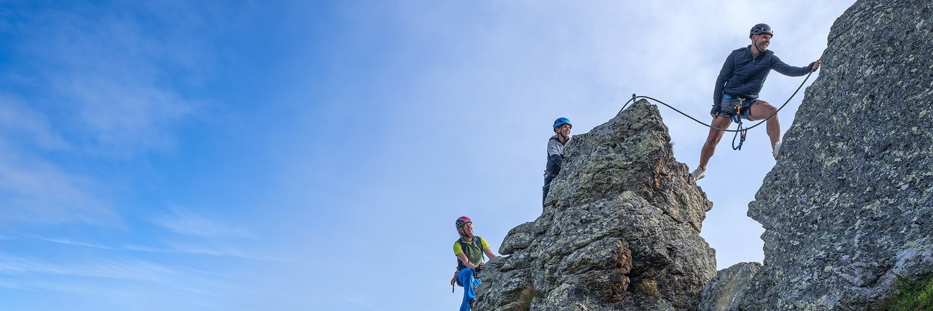 Dieses Bild zeigt eine Gruppe, die auf der Schlossalm auf einem felsigen Klettersteig in luftiger Höhe klettert