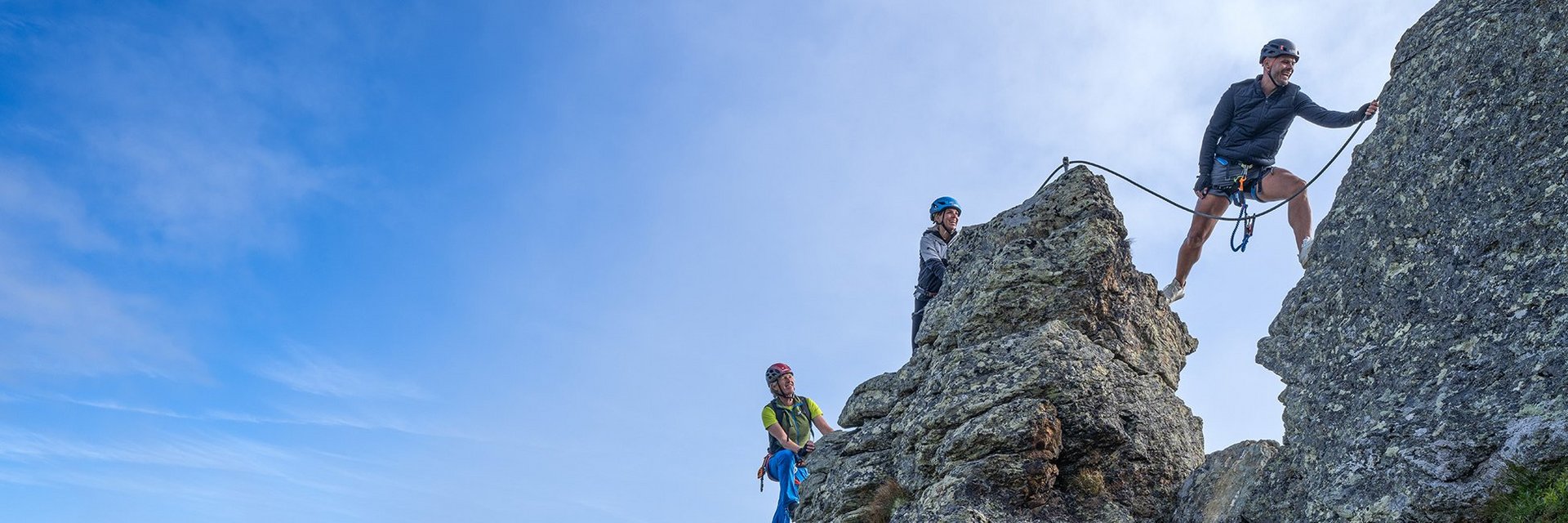 Dieses Bild zeigt eine Gruppe, die auf der Schlossalm auf einem felsigen Klettersteig in luftiger Höhe klettert