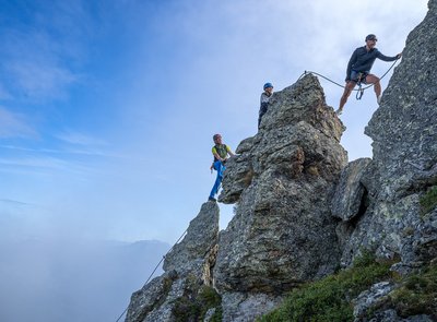 Dieses Bild zeigt eine Gruppe, die auf der Schlossalm auf einem felsigen Klettersteig in luftiger Höhe klettert