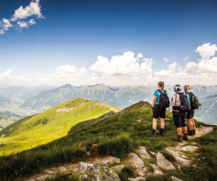 Dieses Bild zeigt drei Wanderer, die in Gastein wandern und die Aussicht auf dem Gipfel genießen