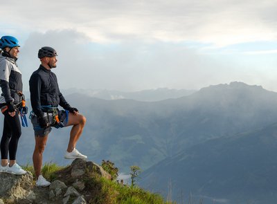 Dieses Bild zeigt ein Paar, dass nach einem absolviertem Klettersteig auf der Schlossalm zufrieden in die Ferne sieht und die Berge bewundert