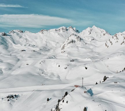 Drohnenaufnahme von traumhaftem Winter-Bergpanorama mit Piste H4 und Schlossalmblick