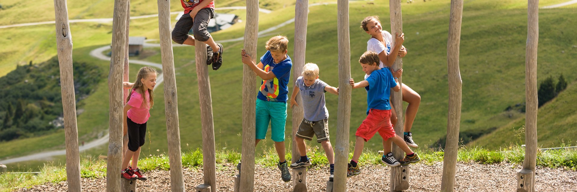 Dieses Bild zeigt eine Gruppe von Kindern, die in einen Pacour aus Baumstämmen klettert