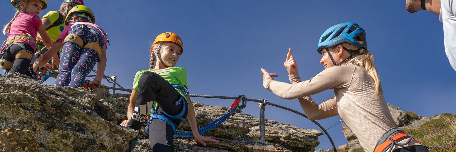 Eine Familie beim gesicherten Klettern am Übungsklettersteig auf der Schlossalm.