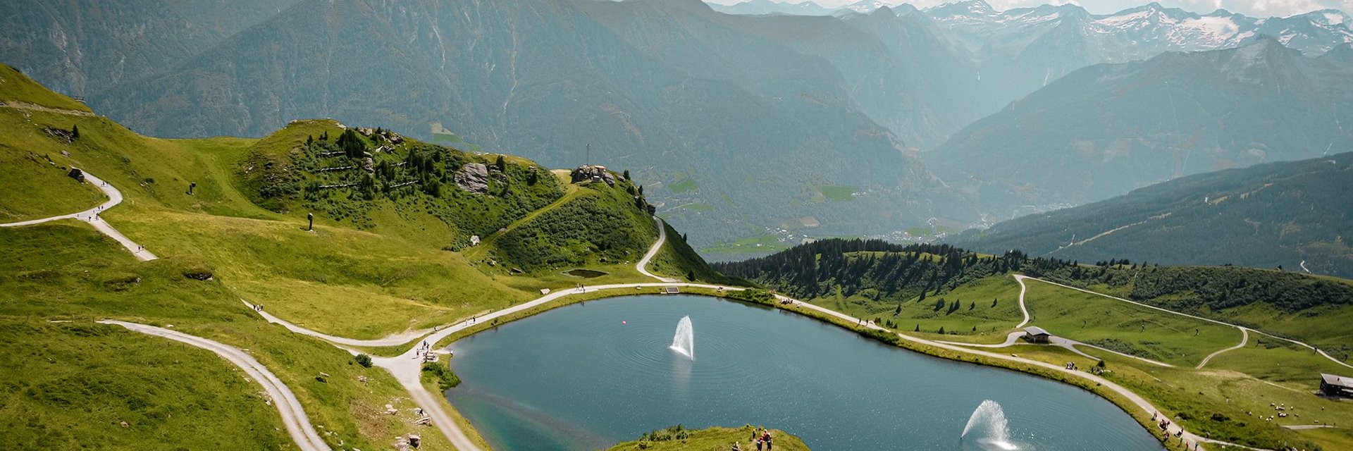 Dieses Bild zeigt eine Luftaufnahme von dem Schlossalmsee mit zwei Wasserfontänen