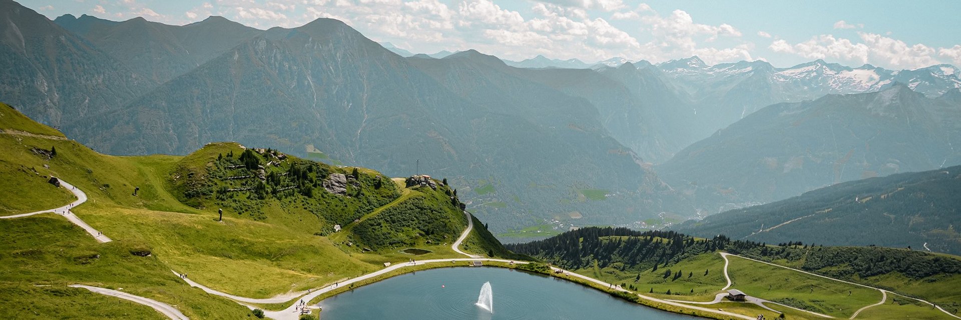 Dieses Bild zeigt eine Luftaufnahme von dem Schlossalmsee mit zwei Wasserfontänen