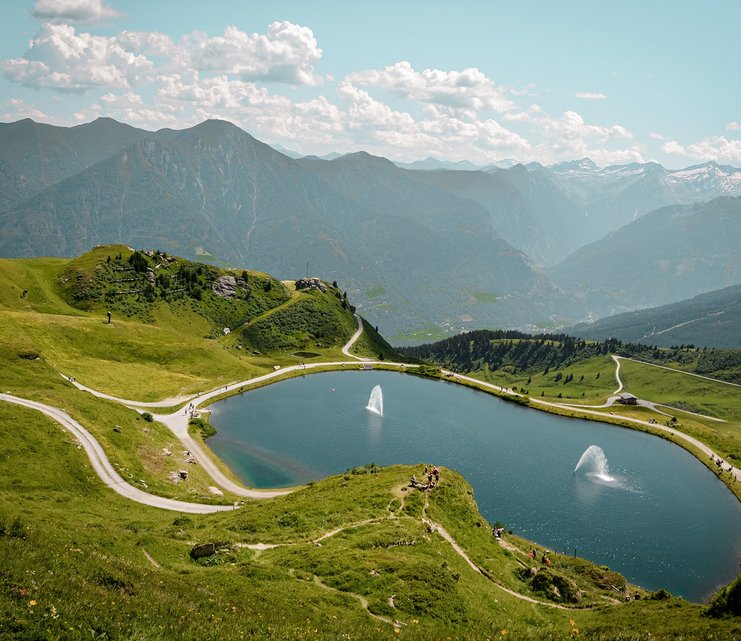Dieses Bild zeigt eine Luftaufnahme von dem Schlossalmsee mit zwei Wasserfontänen