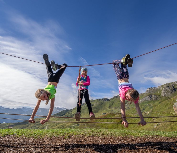 Dieses Bild zeigt drei Mädchen, die im Slackline-Park auf der Schlossalm auf einem Seil turnen