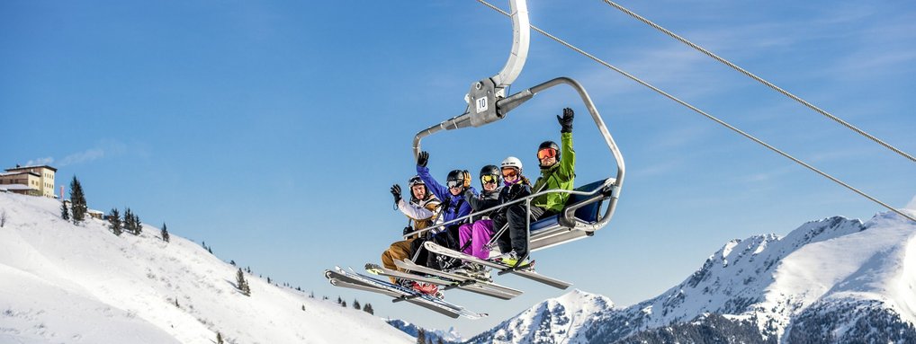 Dieses Bild zeigt eine Gruppe von Skifahrern, die auf einem Sessellift in Gastein sitzen