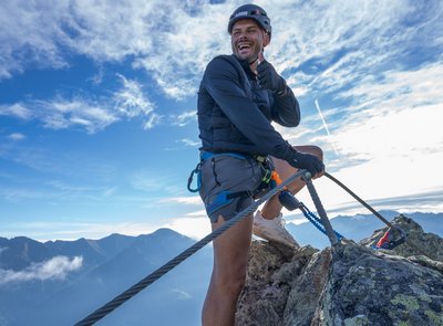 Dieses Bild zeigt einen begeisterten Kletterer, der auf der Schlossalm einen Klettersteig absolviert