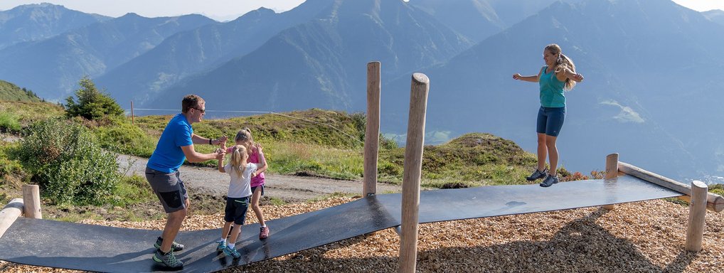 Dieses Bild zeigt eine Familie, die auf einem Trampolin Steg auf der Schlossalm springt