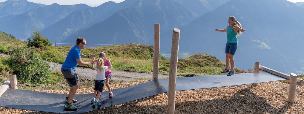 Dieses Bild zeigt eine Familie, die auf einem Trampolin Steg auf der Schlossalm springt