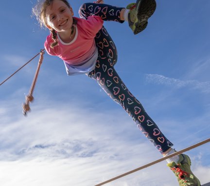 Dieses Bild zeigt ein Mädchen, dass im Slackline-Park auf der Schlossalm turnt