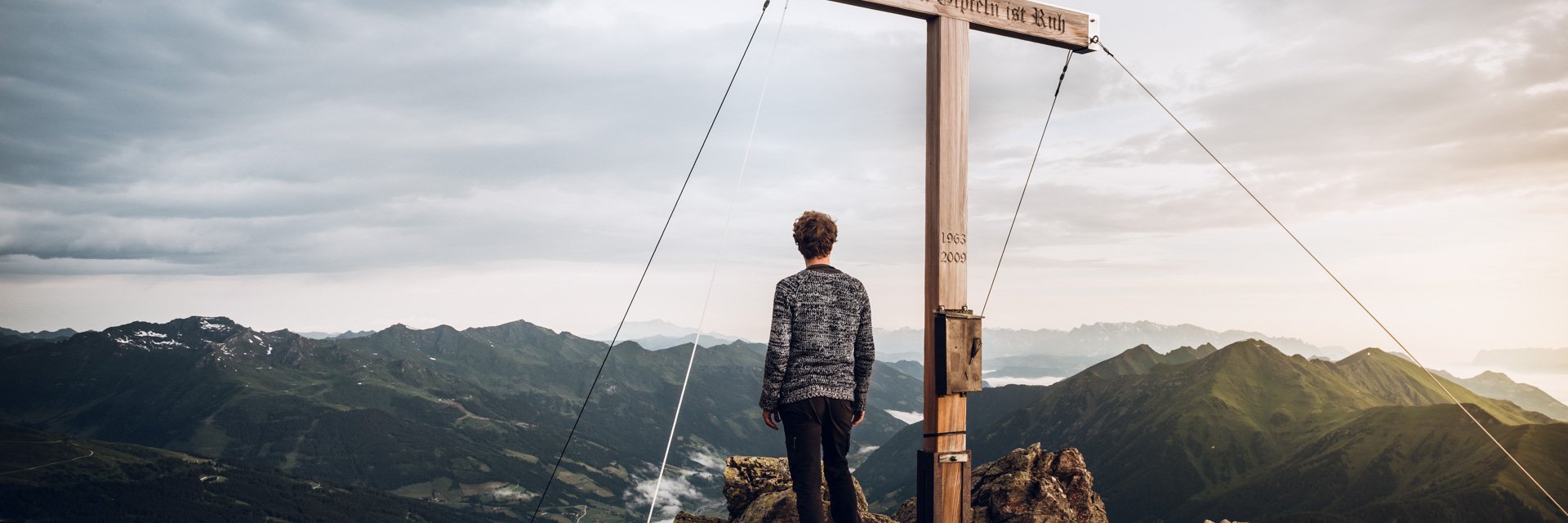 Dieses Bild zeigt einen in die Ferne blickenden Wanderer auf dem Gipfel des Graukogels