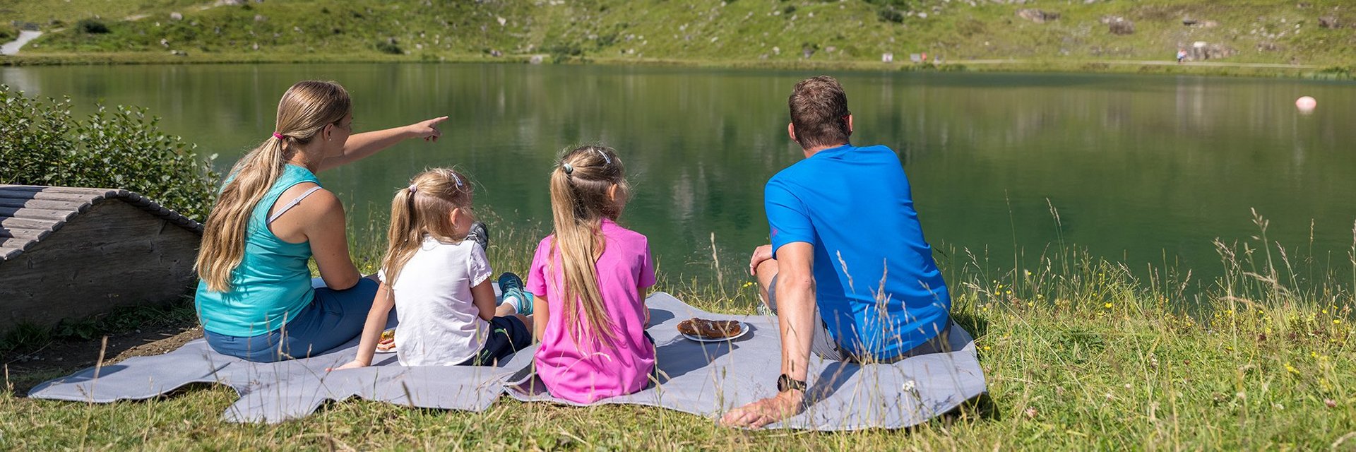 Dieses Bild zeigt eine Familie , die am Schlossalmsee picknickt und in die Ferne sieht