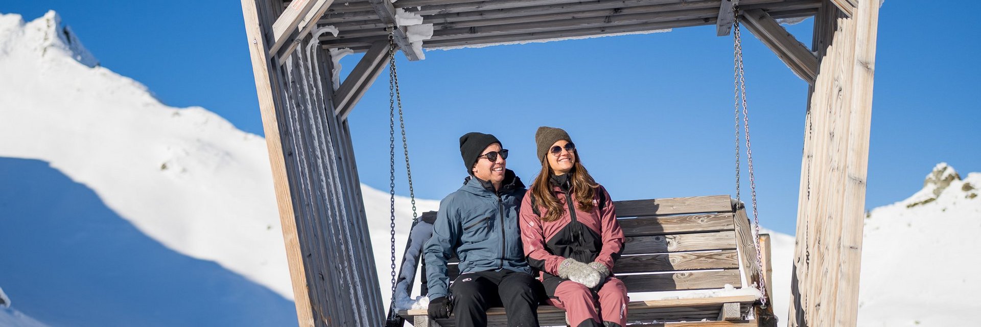 Dieses Bild zeigt ein Paar, dass in einer Hängeschaukel auf der Schlossalm im Winter sitzt