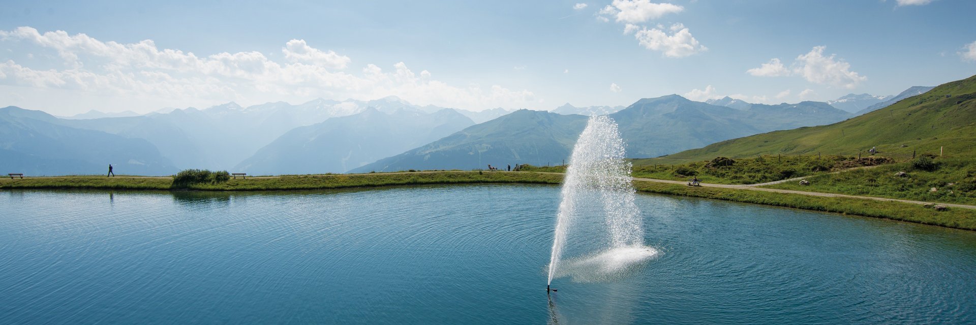 Dieses Bild zeigt den Schlossalmsee mit einer Wasserfontäne in der Mitte