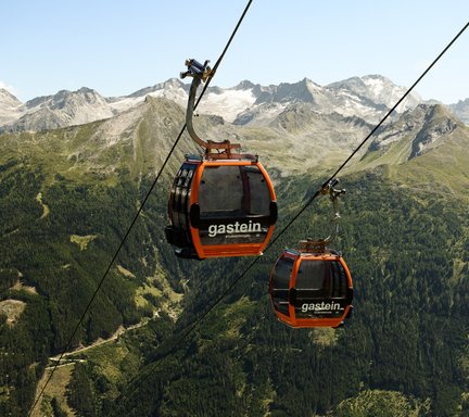 Dieses Bild zeigt zwei Gondeln der Stubnerkogelbahn mit einem sommerlichen Bergpanorama im Hintergrund