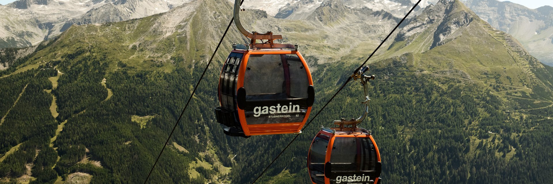 Dieses Bild zeigt zwei Gondeln der Stubnerkogelbahn mit einem sommerlichen Bergpanorama im Hintergrund