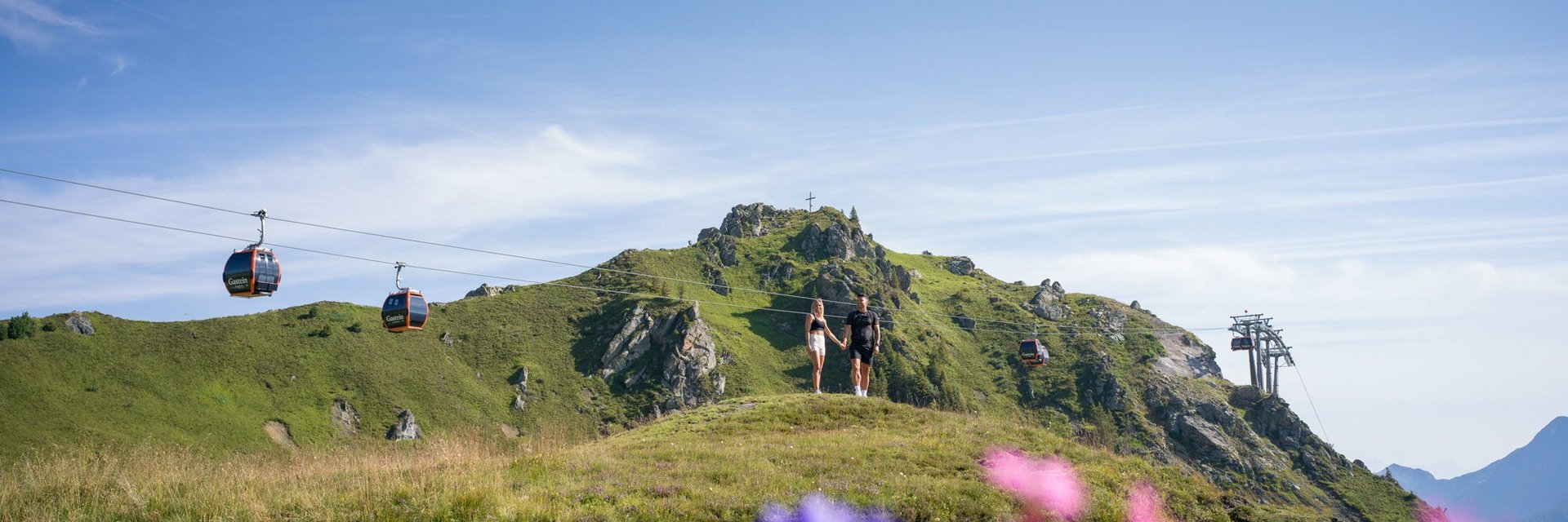 Dieses Bild zeigt ein Paar, das auf der Schlossalm wandert und die Natur genießt. Im Hintergrund sind Gondeln zu sehen. 