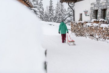 Rodler zieht den Schlitten Richtung Rodelbahn